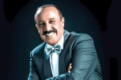 سعيد الناصري مبتسماً يرتدي نظارة وبدلة سوداء وربطة عنق