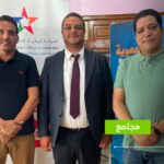 ثلاثة رجال يقفون بجانب لافتة SNRTNews.
