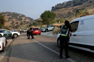 سيارة إطفاء ورجال إطفاء على الطريق السريع يتصدون لحريق غابة.