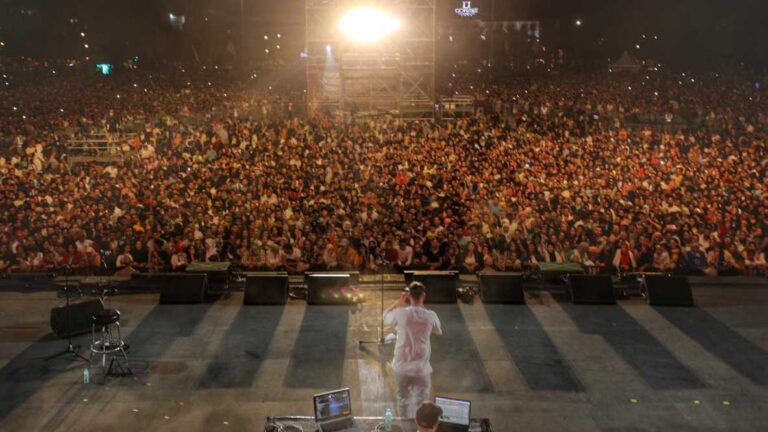 جمهور غفير يتفاعل مع عرض فني لفرقة موسيقية على المسرح ليلاً.