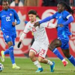 لاعب كرة قدم أبيض القميص يتصدى له منافس أزرق
