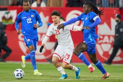 لاعب كرة قدم أبيض القميص يتصدى له منافس أزرق