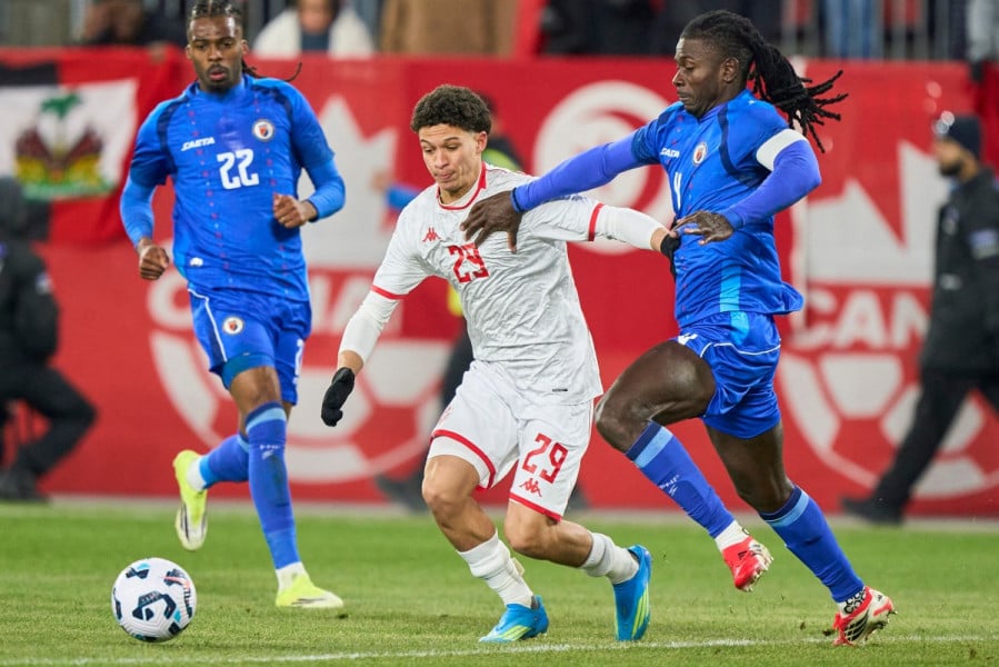 لاعب كرة قدم أبيض القميص يتصدى له منافس أزرق