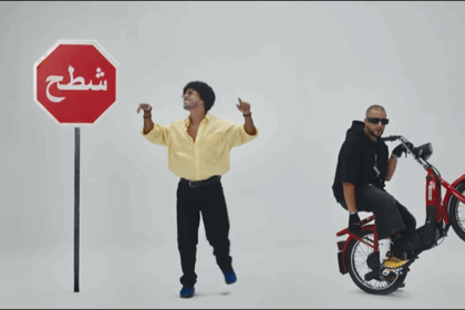 شابان يقفان بجانب علامة توقف مكتوب عليها كلمة عربية.