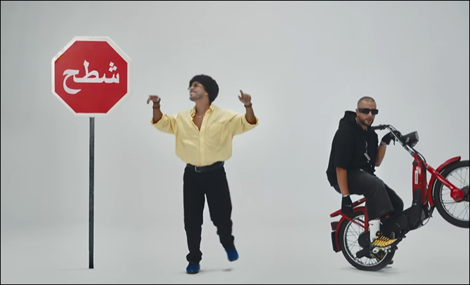 شابان يقفان بجانب علامة توقف مكتوب عليها كلمة عربية.