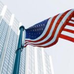 علم الولايات المتحدة يرفرف أمام ناطحة سحاب