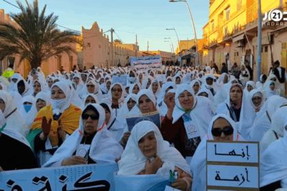 امرأة ترفع لافتة وسط حشد كبير في منطقة صحراوية.