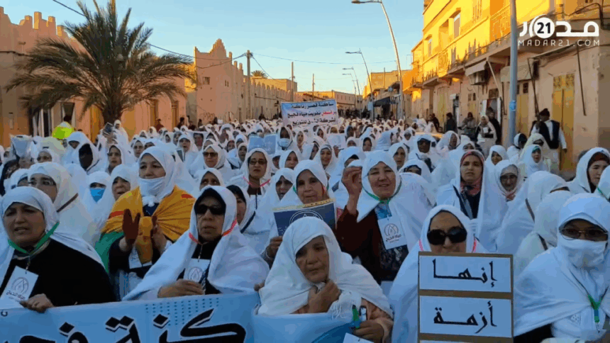 امرأة ترفع لافتة وسط حشد كبير في منطقة صحراوية.