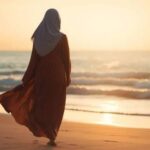 امرأة تسير على الشاطئ نحو الغروب