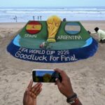 مشجعون يتفاعلون مع مجسم لكأس العالم في استاد كرة قدم.
