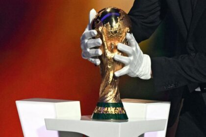 شخص يرتدي قفازات يحمل كأس العالم الذهبية.
