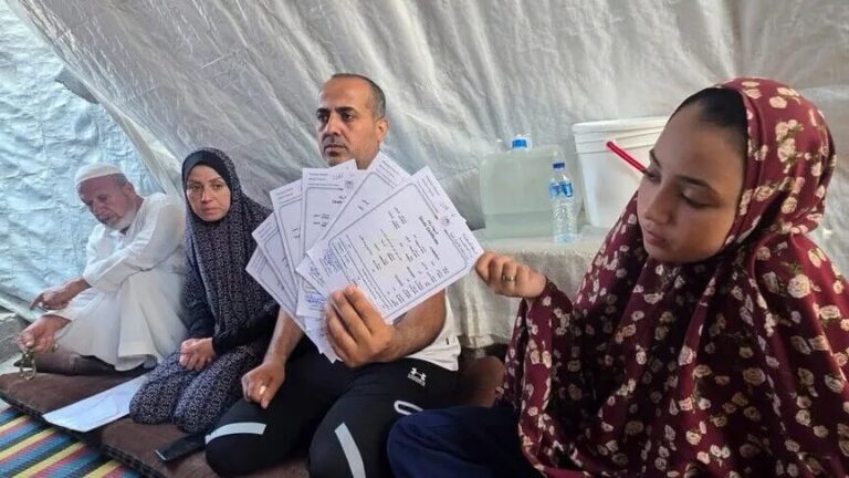 أحمد السيقلي جالسًا مع عائلته في ملجأ مؤقت بغزة.