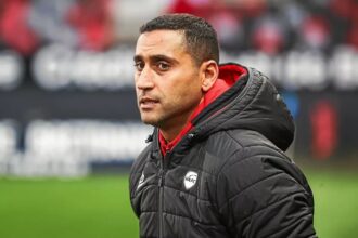 أحمد قنطاري يرتدي سترة التدريب ويقف على أرض الملعب.