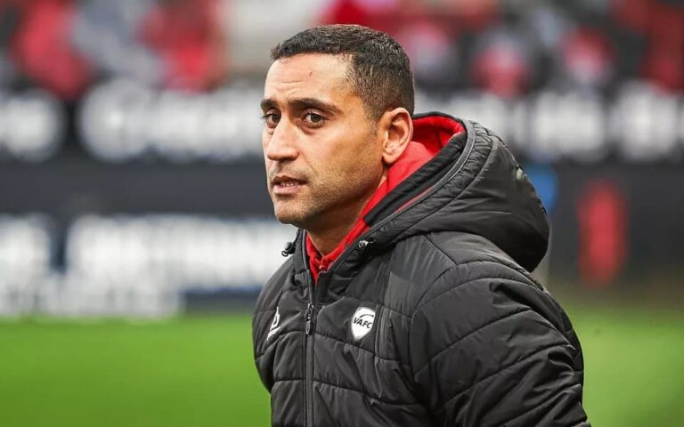 أحمد قنطاري يرتدي سترة التدريب ويقف على أرض الملعب.