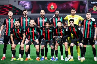 لاعبو الجيش الملكي بقمصان مخططة حمراء وسوداء على أرضية الملعب.