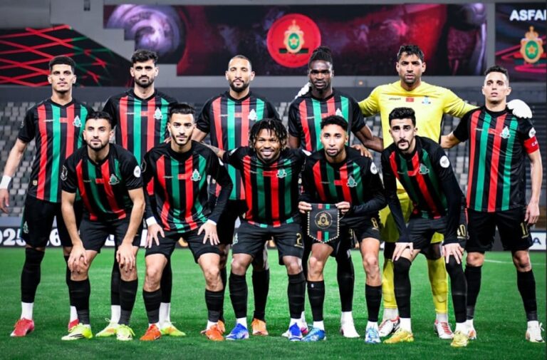 لاعبو الجيش الملكي بقمصان مخططة حمراء وسوداء على أرضية الملعب.