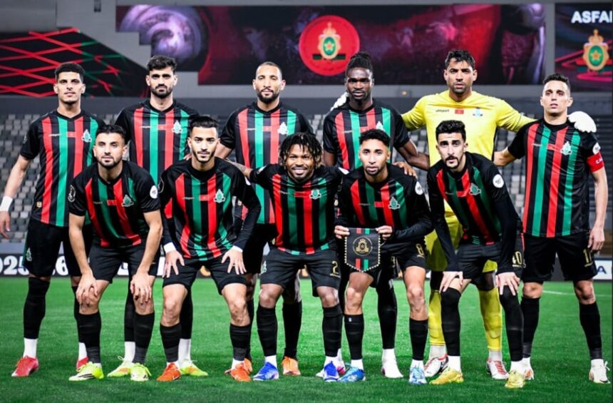 لاعبو الجيش الملكي بقمصان مخططة حمراء وسوداء على أرضية الملعب.