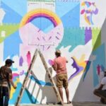 ثلاثة رجال يرسمون جدارية ملونة في أصيلة