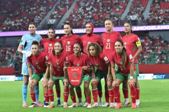 لاعبات المنتخب المغربي لكرة القدم النسوية يحملن قميص عليه شعار المغرب.