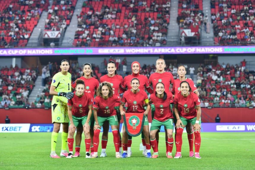 منتخب المغرب النسوي لكرة القدم يرتدي زياً رياضياً ويقف في الملعب.