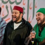 ثلاثة رجال يرتدون ملابس تقليدية يبتسمون للكاميرا.