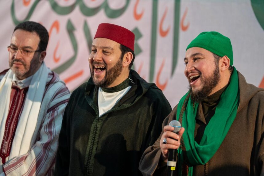 ثلاثة رجال يرتدون ملابس تقليدية يبتسمون للكاميرا.