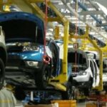 سيارة زرقاء داخل مصنع حديث لإنتاج السيارات.