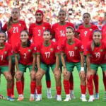 لاعبات كرة قدم فرنسيات بالزي الرسمي ينظرن إلى ملعب عشبي