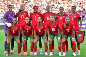 لاعبات كرة قدم فرنسيات بالزي الرسمي ينظرن إلى ملعب عشبي