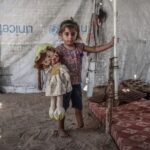طفلة فلسطينية تحمل دمية داخل خيمة نزوح في غزة.