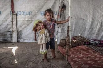 طفلة فلسطينية تحمل دمية داخل خيمة نزوح في غزة.