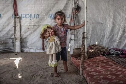 طفلة فلسطينية تحمل دمية داخل خيمة نزوح في غزة.