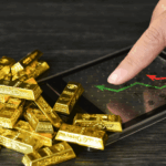 سبائك ذهبية وجهاز إلكتروني على طاولة.