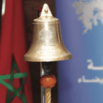 جرس ذهبي بشكل تفاحة بجانب العلم المغربي