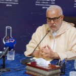 عبد الإله ابن كيران يتحدث عبر ميكروفون أزرق.
