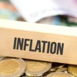 مكعبات خشبية تحمل كلمة "تضخم" مع عملات معدنية.