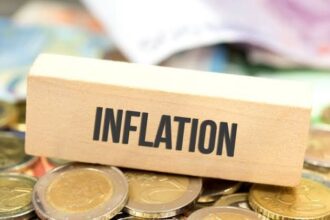 مكعبات خشبية تحمل كلمة "تضخم" مع عملات معدنية.