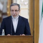 وزير إيراني يتحدث من منبر أمام علم بلاده