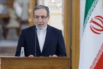 وزير إيراني يتحدث من منبر أمام علم بلاده
