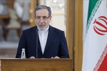 وزير إيراني يتحدث من منبر أمام علم بلاده