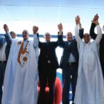 رجال يحتفلون ويمسكون بأيديهم ملفوفة باللونين الأزرق والبرتقالي.