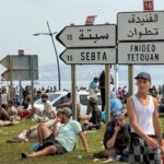 أشخاص يجلسون على عشب قرب لافتة إرشادية