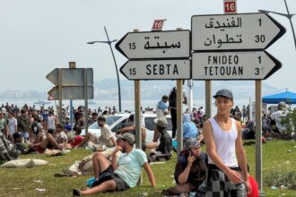 أشخاص يجلسون على عشب قرب لافتة إرشادية
