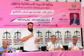 رجل يتحدث في ميكروفون أمام خلفية وردية.