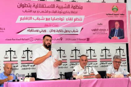 رجل يتحدث في ميكروفون أمام خلفية وردية.