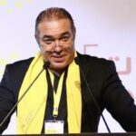 رجل يرتدي بدلة يتحدث في الميكروفونات