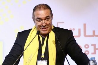 رجل يرتدي بدلة يتحدث في الميكروفونات