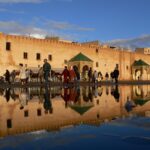 أشخاص يسيرون أمام مبانٍ صفراء وخضراء.