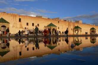 أشخاص يسيرون أمام مبانٍ صفراء وخضراء.