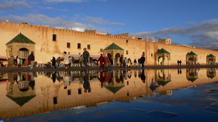 أشخاص يسيرون أمام مبانٍ صفراء وخضراء.